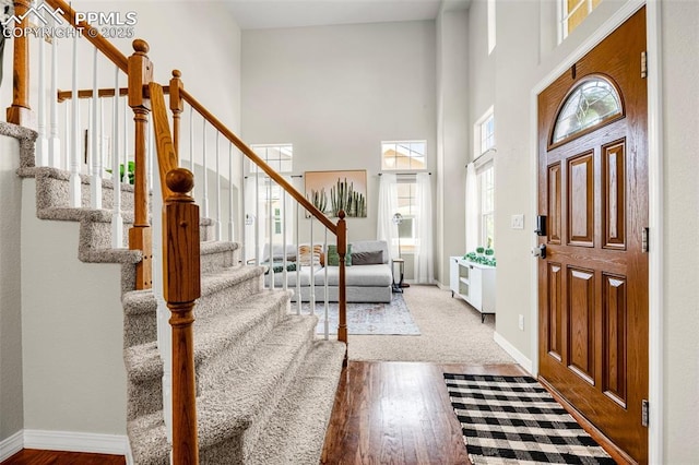 9883 Red Sage Dr, Colorado Springs, CO 80920 - foyer entrance featuring stairs, a towering ceiling, wood finished floors, and baseboards