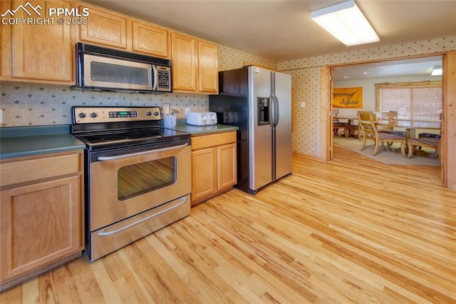 65 Sunshine Loop, Fairplay, CO 80440 - kitchen with stainless steel appliances, light wood-style flooring, light brown cabinets, wallpapered walls, and dark countertops