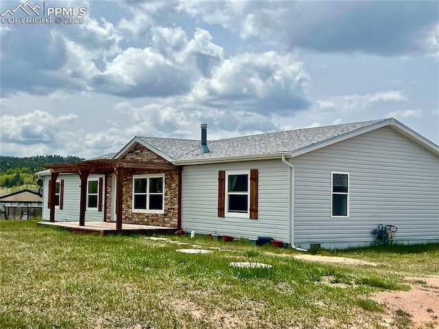 527 Golden Grain Ln, Divide, CO 80814 - rear view of house featuring a lawn, stone siding, a shingled roof, and a wooden deck
