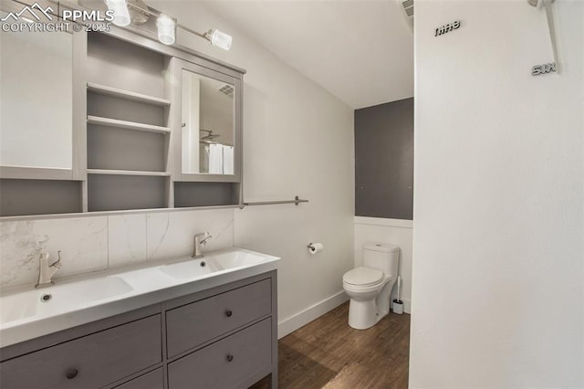 527 Golden Grain Ln, Divide, CO 80814 - bathroom with wood finished floors, double vanity, toilet, backsplash, and baseboards