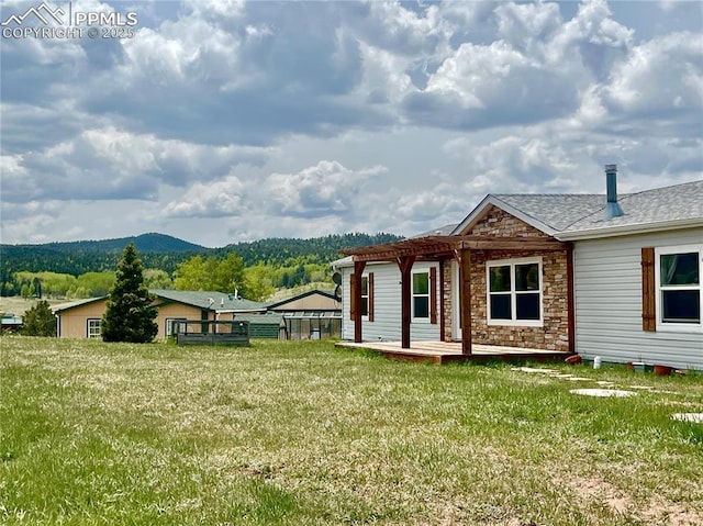 527 Golden Grain Ln, Divide, CO 80814 - view of property exterior with a deck with mountain view, stone siding, a lawn, and a shingled roof
