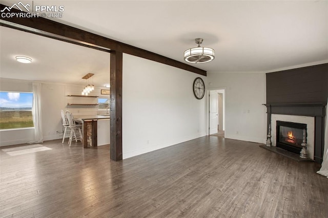 527 Golden Grain Ln, Divide, CO 80814 - unfurnished living room with a glass covered fireplace, wood finished floors, a chandelier, and baseboards