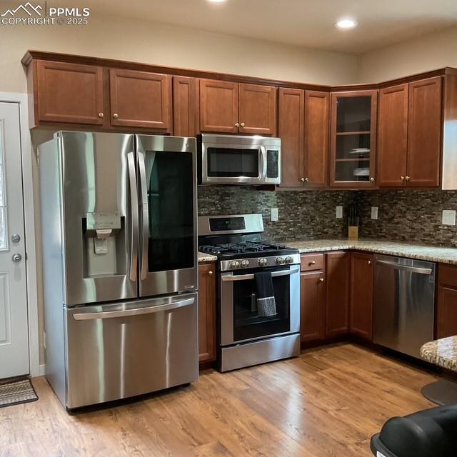 71 Mt Elbert Dr, Florissant, CO 80816 - kitchen featuring appliances with stainless steel finishes, light stone countertops, backsplash, light wood-style flooring, and recessed lighting