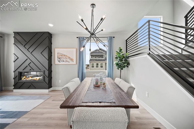 3077 Curly Grv, Colorado Springs, CO 80922 - dining area with a chandelier, stairs, wood finished floors, baseboards, and a large fireplace
