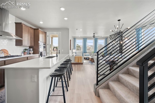 3071 Curly Grv, Colorado Springs, CO 80922 - kitchen featuring wall chimney exhaust hood, a sink, gas stovetop, open floor plan, and tasteful backsplash