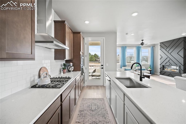 3071 Curly Grv, Colorado Springs, CO 80922 - kitchen with a sink, wall chimney range hood, stainless steel appliances, open floor plan, and light wood-style floors