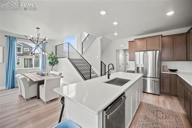 3071 Curly Grv, Colorado Springs, CO 80922 - kitchen with stainless steel appliances, a sink, light wood-style floors, a chandelier, and light countertops
