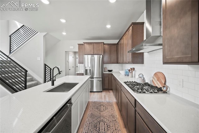 3071 Curly Grv, Colorado Springs, CO 80922 - kitchen with a sink, appliances with stainless steel finishes, wall chimney range hood, light wood-style flooring, and decorative backsplash