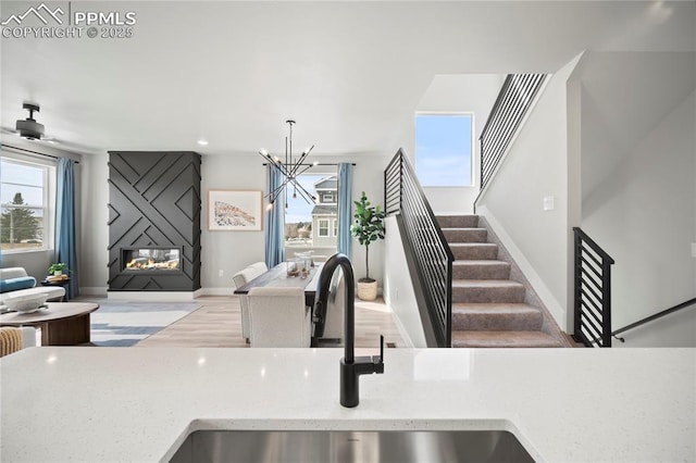 3071 Curly Grv, Colorado Springs, CO 80922 - kitchen with a sink, light stone countertops, a chandelier, a large fireplace, and baseboards