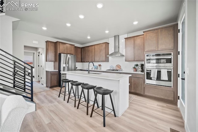 3071 Curly Grv, Colorado Springs, CO 80922 - kitchen featuring wall chimney range hood, a breakfast bar, appliances with stainless steel finishes, a sink, and backsplash