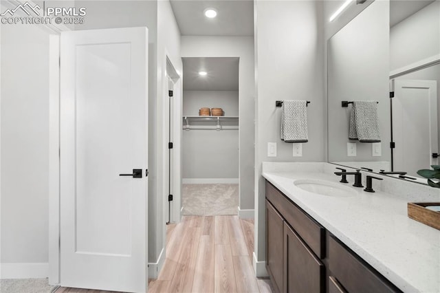 3071 Curly Grv, Colorado Springs, CO 80922 - bathroom with vanity, a spacious closet, baseboards, wood finished floors, and recessed lighting
