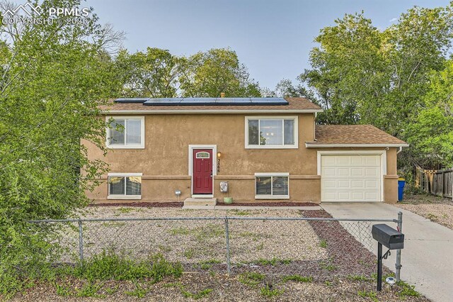 3566 Verde Dr, Colorado Springs, CO 80910 - split foyer home featuring a garage, stucco siding, driveway, and solar panels