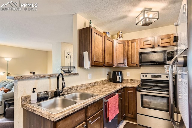 3566 Verde Dr, Colorado Springs, CO 80910 - kitchen featuring stainless steel appliances, a sink, light countertops, a textured ceiling, and a peninsula