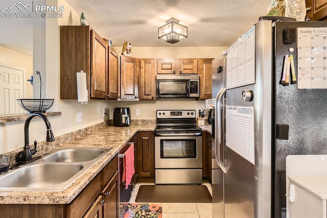 3566 Verde Dr, Colorado Springs, CO 80910 - kitchen featuring stainless steel appliances, a sink, light countertops, light tile patterned floors, and a textured ceiling