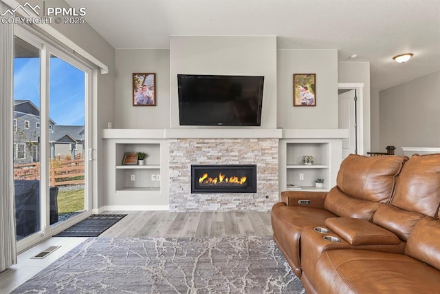 10192 Kentwood Dr, Colorado Springs, CO 80924 - living area with wood finished floors, a stone fireplace, built in shelves, and baseboards
