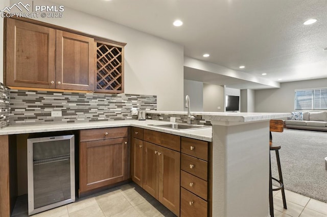 10192 Kentwood Dr, Colorado Springs, CO 80924 - kitchen with wine cooler, a peninsula, a sink, open floor plan, and a breakfast bar area