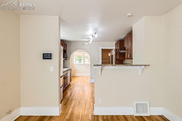 228 N Hancock Ave, Colorado Springs, CO 80903 - kitchen featuring a kitchen breakfast bar, under cabinet range hood, light stone countertops, a peninsula, and light wood-type flooring