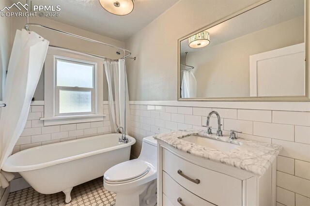 228 N Hancock Ave, Colorado Springs, CO 80903 - full bath featuring tile walls, vanity, toilet, and wainscoting