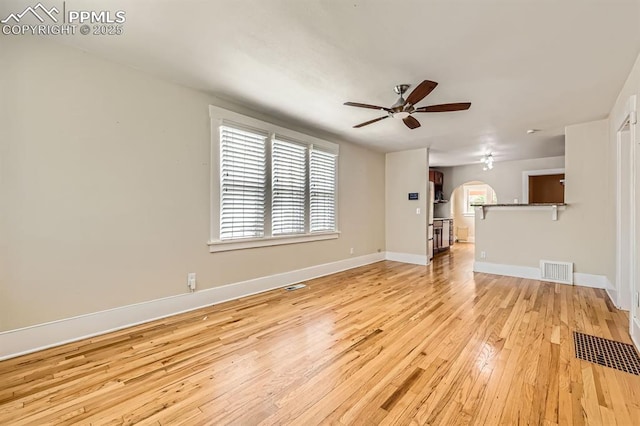 228 N Hancock Ave, Colorado Springs, CO 80903 - unfurnished living room featuring arched walkways, a ceiling fan, light wood-type flooring, and baseboards