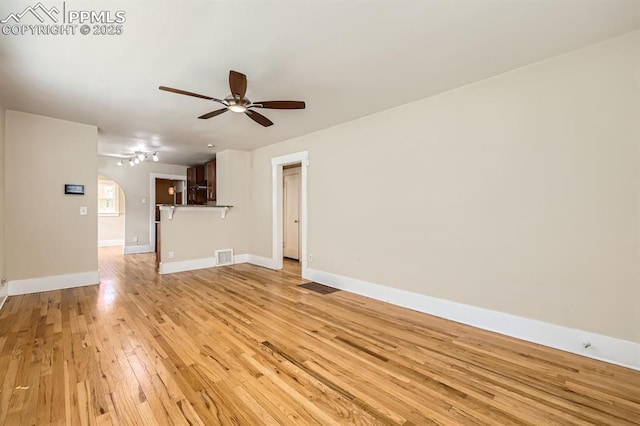 228 N Hancock Ave, Colorado Springs, CO 80903 - unfurnished living room featuring ceiling fan, arched walkways, light wood-style floors, and baseboards