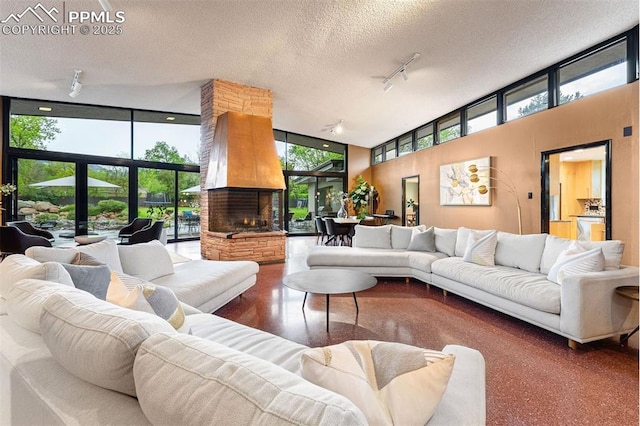 312 Lake Ave, Colorado Springs, CO 80906 - living area with a high ceiling, track lighting, a textured ceiling, a stone fireplace, and floor to ceiling windows