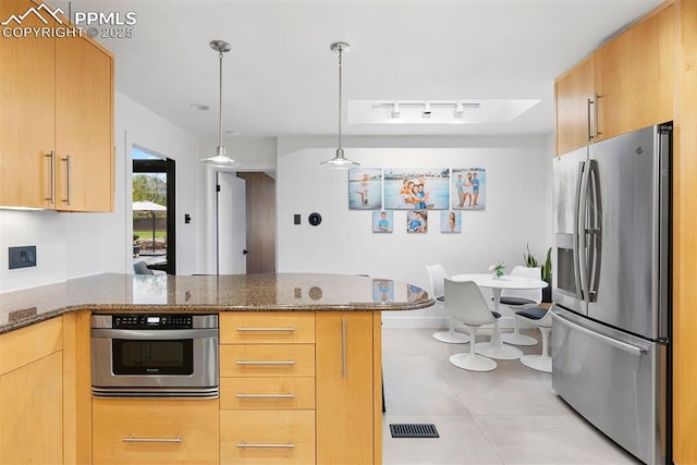 312 Lake Ave, Colorado Springs, CO 80906 - kitchen featuring stainless steel appliances, a peninsula, light tile patterned floors, dark stone countertops, and decorative light fixtures