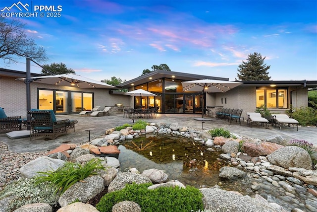 312 Lake Ave, Colorado Springs, CO 80906 - back of house at dusk featuring a patio area and brick siding