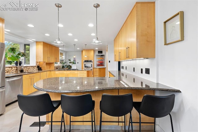 312 Lake Ave, Colorado Springs, CO 80906 - kitchen featuring appliances with stainless steel finishes, a peninsula, tasteful backsplash, recessed lighting, and dark stone counters
