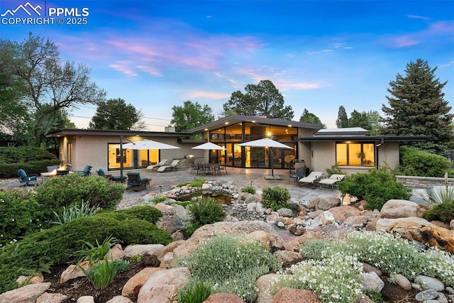 312 Lake Ave, Colorado Springs, CO 80906 - back of house at dusk featuring a patio and brick siding