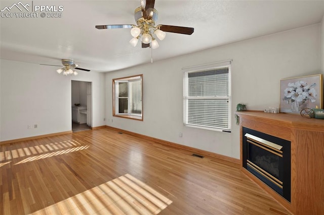 229 E Washington St, Colorado Springs, CO 80907 - unfurnished living room featuring ceiling fan, light wood-style flooring, a glass covered fireplace, and baseboards
