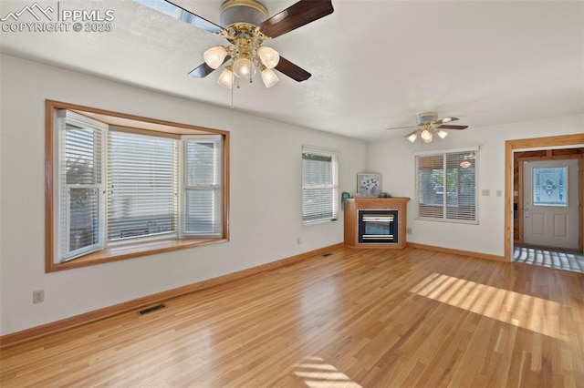 229 E Washington St, Colorado Springs, CO 80907 - unfurnished living room featuring a ceiling fan, baseboards, light wood-style floors, and a glass covered fireplace