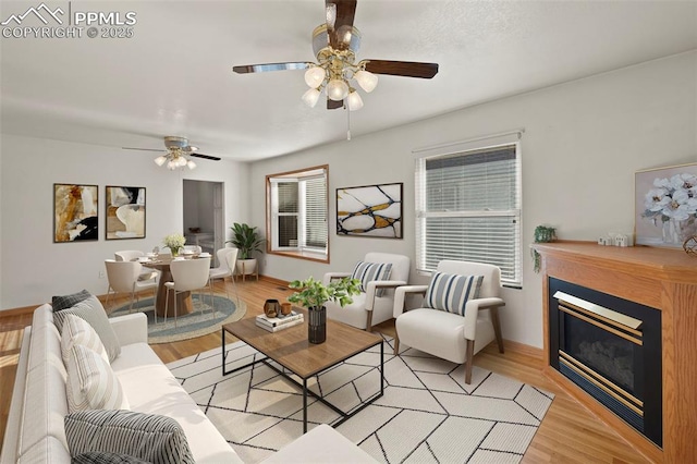 229 E Washington St, Colorado Springs, CO 80907 - living room featuring a ceiling fan, a glass covered fireplace, light wood-style flooring, and baseboards