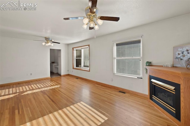 229 E Washington St, Colorado Springs, CO 80907 - unfurnished living room with wood finished floors, a ceiling fan, a glass covered fireplace, and baseboards