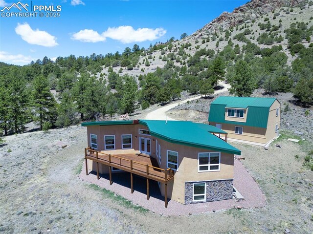 610 Matterhorn Cir, Westcliffe, CO 81252 - back of house featuring stucco siding, a deck with mountain view, metal roof, and stone siding