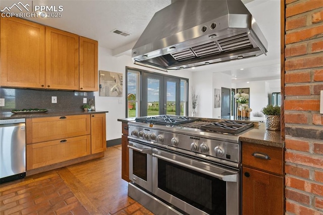 16030 Alta Plaza Cir, Peyton, CO 80831 - kitchen with stainless steel appliances, wall chimney range hood, backsplash, brown cabinetry, and french doors