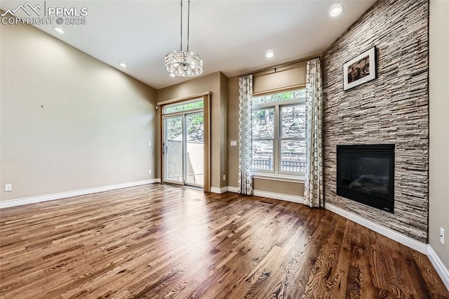 2252 Conservatory Pt, Colorado Springs, CO 80918 - unfurnished living room featuring wood finished floors, baseboards, a stone fireplace, a chandelier, and recessed lighting