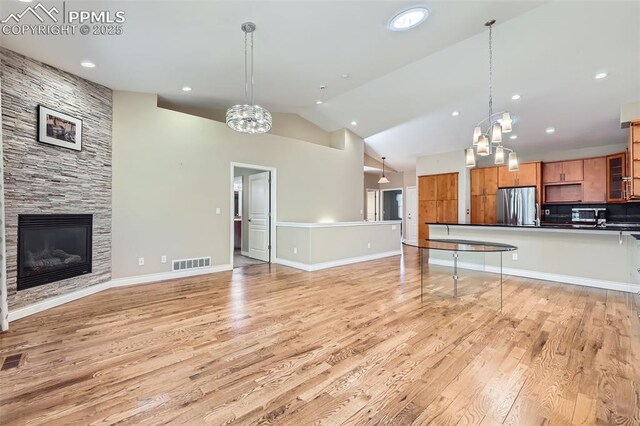 2252 Conservatory Pt, Colorado Springs, CO 80918 - kitchen featuring freestanding refrigerator, brown cabinetry, dark countertops, open floor plan, and light wood-style floors