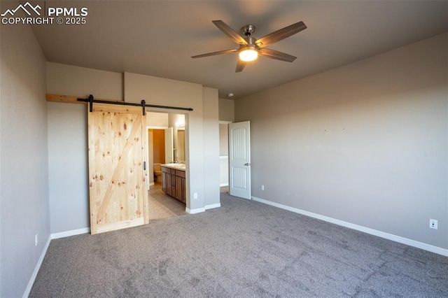 1985 Reed Grass Way, Colorado Springs, CO 80915 - unfurnished bedroom with carpet floors, a barn door, baseboards, ensuite bathroom, and ceiling fan