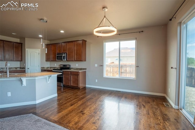 1985 Reed Grass Way, Colorado Springs, CO 80915 - kitchen featuring stainless steel appliances, dark wood-style flooring, a kitchen bar, pendant lighting, and recessed lighting