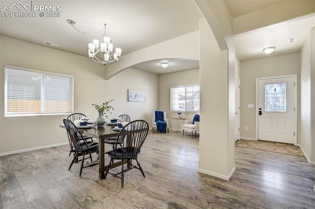 7923 Wagonwood Pl, Colorado Springs, CO 80908 - dining room featuring arched walkways, wood finished floors, a chandelier, and baseboards