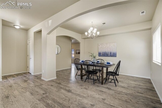 7923 Wagonwood Pl, Colorado Springs, CO 80908 - dining space featuring wood finished floors, a chandelier, baseboards, and arched walkways