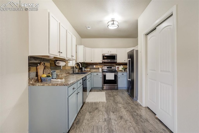 7923 Wagonwood Pl, Colorado Springs, CO 80908 - kitchen featuring stainless steel appliances, a sink, light wood-type flooring, gray cabinets, and tasteful backsplash