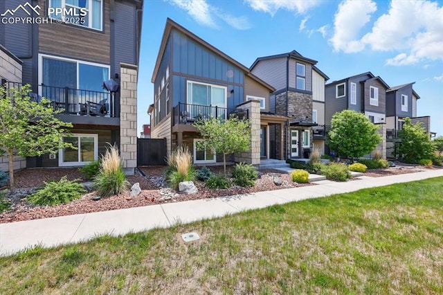 2454 Jazzy Lady Ct, Colorado Springs, CO 80922 - contemporary home with board and batten siding, stone siding, a residential view, and a front yard