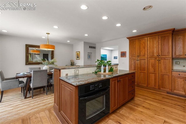 490 Wintery Cir, Colorado Springs, CO 80919 - kitchen with black oven, recessed lighting, brown cabinets, and light wood-style floors
