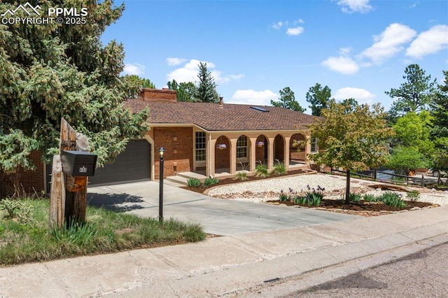 490 Wintery Cir, Colorado Springs, CO 80919 - view of front of home with concrete driveway, an attached garage, covered porch, a chimney, and brick siding