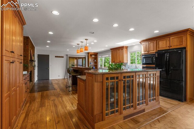 490 Wintery Cir, Colorado Springs, CO 80919 - kitchen featuring black appliances, brown cabinets, recessed lighting, glass insert cabinets, and hardwood / wood-style floors
