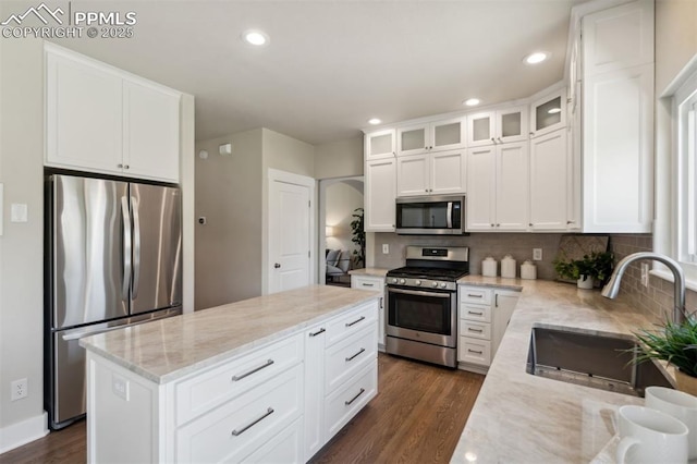 9969 Bridgeport Dr, Colorado Springs, CO 80920 - kitchen featuring appliances with stainless steel finishes, a sink, backsplash, dark wood finished floors, and a kitchen island