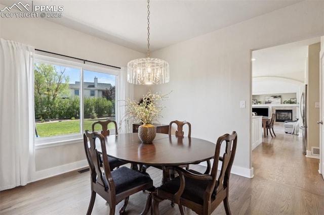 9969 Bridgeport Dr, Colorado Springs, CO 80920 - dining room featuring wood finished floors, a chandelier, baseboards, and a fireplace