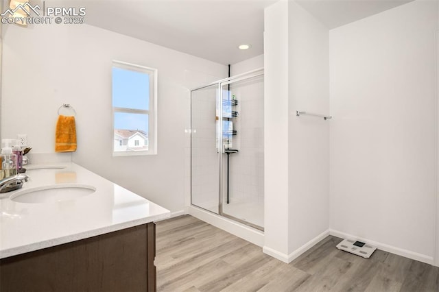 10046 Keating Dr, Peyton, CO 80831 - bathroom with wood finished floors, a stall shower, double vanity, baseboards, and recessed lighting