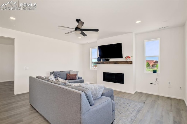 10046 Keating Dr, Peyton, CO 80831 - living room featuring wood finished floors, a glass covered fireplace, ceiling fan, baseboards, and recessed lighting